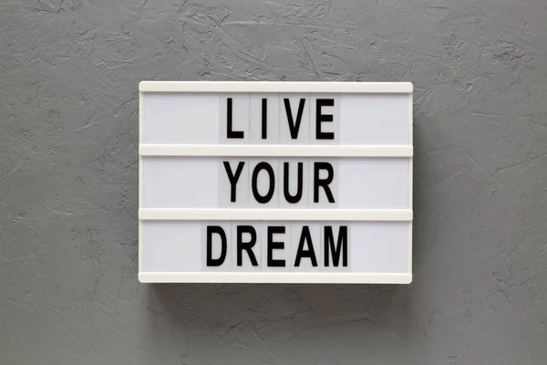 \'Live your dream\' words on a lightbox on a gray surface, top vie