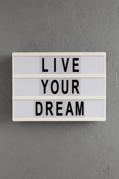 \'Live your dream\' words on a lightbox on a gray surface, top vie