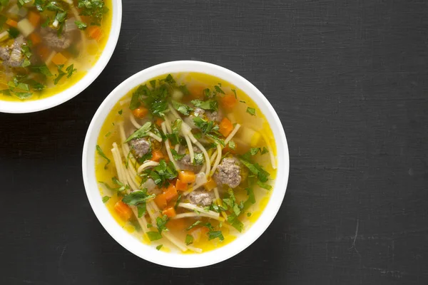 Siyah bir yüzey üzerinde beyaz kâselerde ev yapımı Sopa a a La Minuta.