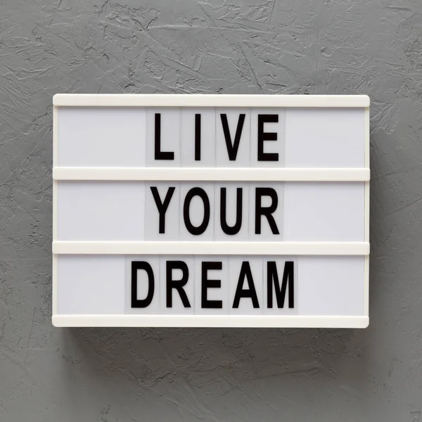 \'Live your dream\' words on a lightbox on a gray background, top