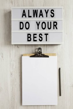 Modern bir panoda her zaman elinden geleni yap, beyaz ahşap zemin üzerinde boş bir kağıt olan bir pano, üst görünüm. Yukarıdan, dümdüz uzanmış. 