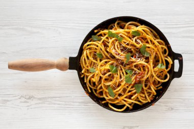 Ev yapımı Bucatini, beyaz ahşap arka planda dökme demir bir tavada Amatriciana Pasta. Dümdüz, tepede. Yakın plan..