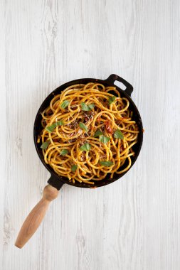 Ev yapımı Bucatini, beyaz ahşap arka planda dökme demir bir tavada Amatriciana Pasta. Düz uzanın, başınızın üstünde.