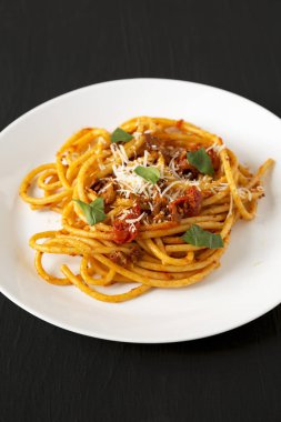 Ev yapımı Bucatini tüm Amatriciana Makarnaları siyah arka planda beyaz bir tabakta, yan manzaralı. Yakın plan..