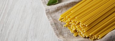 Beyaz ahşap arka planda, düşük açılı, pişmemiş Bucatini Pasta. Metin için boşluk.