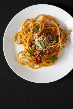 Ev yapımı Bucatini, Amatriciana Makarnası. Siyah bir yüzey üzerinde beyaz bir tabakta. Dümdüz, tepeden, yukarıdan.