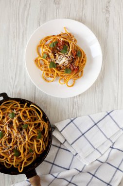 Ev yapımı Bucatini beyaz tahta bir masada beyaz bir tabakta Amatriciana Pasta. Dümdüz, tepeden, yukarıdan.