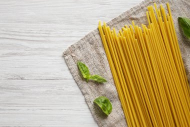 Beyaz ahşap bir masada pişmemiş organik Bucatini Pasta. Yukarıdan, dümdüz, tepeden. Boşluğu kopyala.