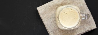 Siyah bir arka plan üzerinde cam bir kavanozda Fıstık ezmesi muz yüzlü, üst görünümü. Düz yatıyordu, yukarıdan, yukarıdan. Kopyalama alanı.