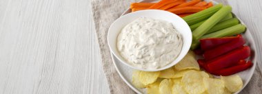 Beyaz ahşap arka planda patates cipsi, kereviz, biber ve havuç ile ev yapımı karamelli soğan dalışı. Metin için boşluk.