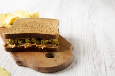 Ev yapımı Fıstık Ezmeli Sandviç ve patates cipsi. Beyaz ahşap arka planda tahta bir tahta üzerinde. Düşük açılı. Boşluğu kopyala.