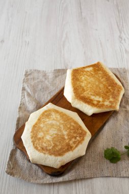 Beyaz ahşap arka planda, ahşap bir tahtanın üzerinde gevrek ev yapımı sığır eti gevreği, yüksek açılı manzara. Boşluğu kopyala.