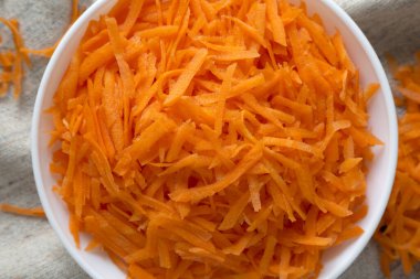 Havuç dilimlenmiş beyaz bir kase içinde, yukarıdan manzaralı. Düz yerde, üst tarafta, tepede. Yakın plan..