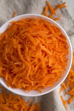 Havuç dilimlenmiş beyaz bir kase içinde kumaş üzerinde, üst manzara. Dümdüz, tepeden, yukarıdan. Yakın plan..