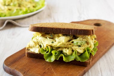 Beyaz ahşap zemin üzerinde ahşap bir tahta üzerinde ev yapımı Tavuklu Sandviç. Düşük açılı. Yakın plan..