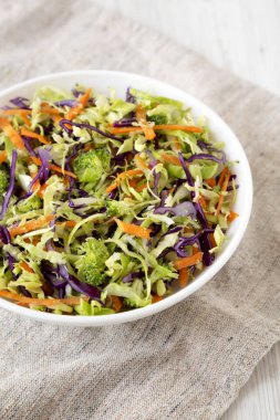 Ev yapımı çiğ brokoli salatası beyaz bir kasede, kumaş üzerinde, yan görünümde. Yakın plan..