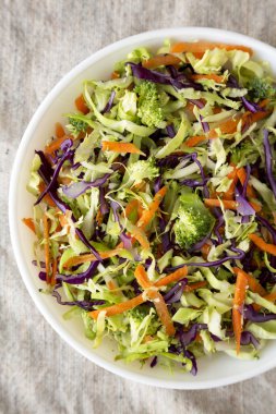 Ev yapımı çiğ brokoli salatası beyaz bir kâse içinde, yukarıdan görünüyor. Üst görünüm, genel görünüm, düz görünüm. 