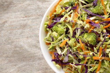 Ev yapımı çiğ brokoli salatası beyaz bir kâse içinde, üst manzara. Yukarıdan, dümdüz yatıyordu. Boşluğu kopyala.