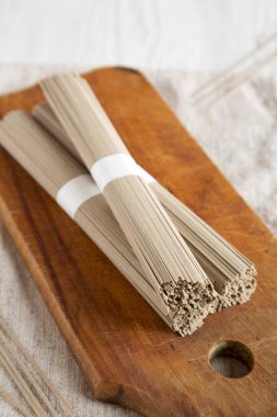 Pişmemiş karabuğday soba eriştesi beyaz ahşap bir masanın üzerinde, düşük açılı bir manzara. Yakın plan..