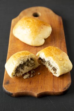 Ev yapımı Rus Bierocks bifteği siyah bir yüzey üzerinde ahşap bir tahta üzerinde, yan görüş. Yakın plan..