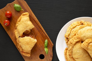 Siyah arka planda soslu ev yapımı İtalyan Panzerotti Calzone. Dümdüz, tepeden, yukarıdan. Boşluğu kopyala.