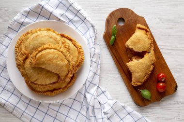 Beyaz ahşap arka planda soslu ev yapımı İtalyan Panzerotti Calzone. Dümdüz, tepeden, yukarıdan.