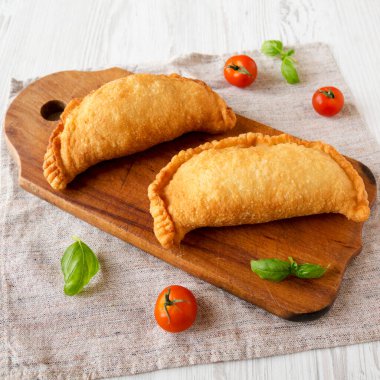 Ev yapımı İtalyan Panzerotti Calzone beyaz ahşap arka planda, düşük açılı ahşap bir tahta üzerinde. Yakın plan..
