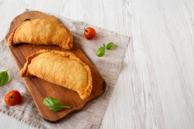 Ev yapımı İtalyan Panzerotti Calzone beyaz ahşap bir masanın üzerinde, alçak açılı. Metin için boşluk.
