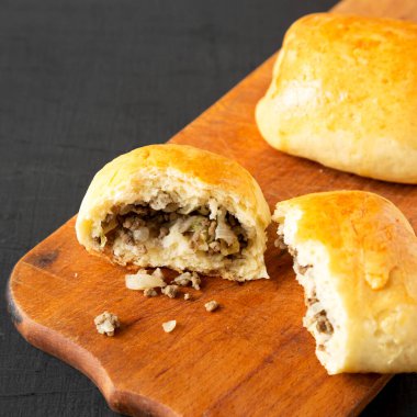 Ev yapımı Rus Bierocks bifteği siyah bir yüzey üzerinde ahşap bir tahta üzerinde, yan görüş. Yakın plan..