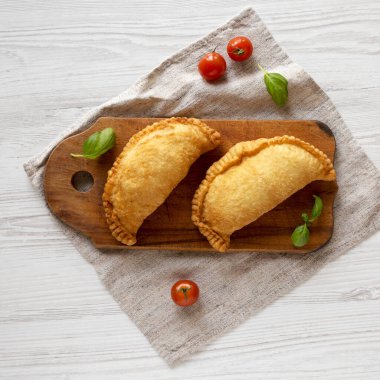 Ev yapımı İtalyan Panzerotti Calzone ahşap bir tahta üzerinde beyaz tahta bir masa, üst manzara. Dümdüz, tepeden, yukarıdan. 