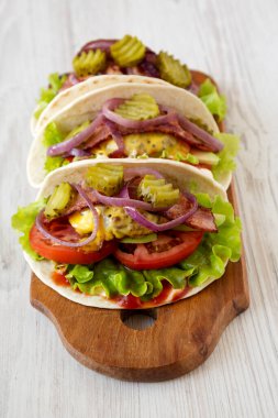 Beyaz ahşap arka planda, düşük açılı, ahşap ahşap bir tahtanın üzerinde ev yapımı çizburgerli taco.. 