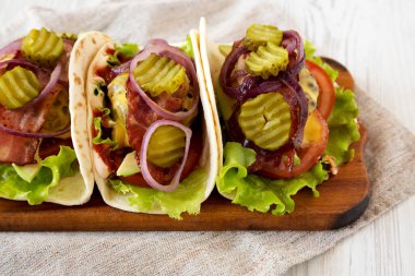 Beyaz ahşap bir masa ve alçak açılı bir manzarayla ev yapımı çizburgerli taco. Yakın plan..