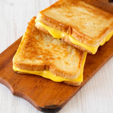 Beyaz ahşap bir masada ahşap bir tahtanın üzerinde ev yapımı peynirli sandviç. Düşük açılı. Yakın plan..