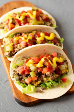 Ev yapımı Cheeseburger Taco 'lar kırsal bir tahta üzerinde gri bir yüzey, düşük açılı.. 