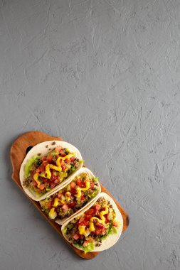 Ev yapımı çizburger Taco 'ları gri bir yüzey üzerinde ahşap bir tahta üzerinde, üst manzara. Dümdüz, tepeden, yukarıdan. Boşluğu kopyala.