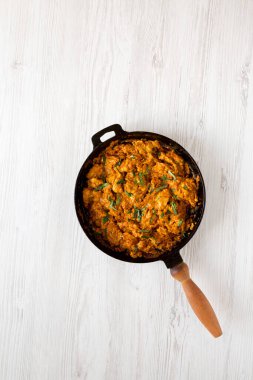 Beyaz ahşap arka planda dökme demir bir tavada ev yapımı tavuk Tikka Masala, üst manzara. Dümdüz, tepeden, yukarıdan. Boşluğu kopyala.