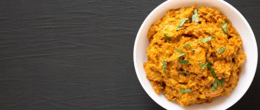 Ev yapımı Tikka Masala tavuğu siyah bir yüzey üzerinde beyaz bir kasede, üst manzara. Dümdüz, tepeden, yukarıdan. Boşluğu kopyala.