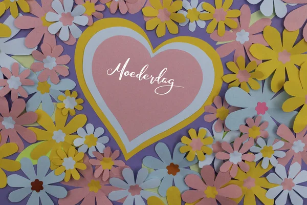 Many paper flowers and stacked paper hearts with the Dutch word Moederdag (Mothers Day).