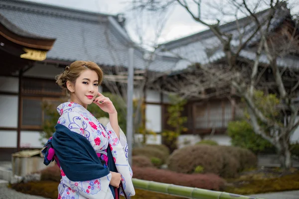 Kvinna klädd i traditionell japansk dräkt promenader under tori — Stockfoto