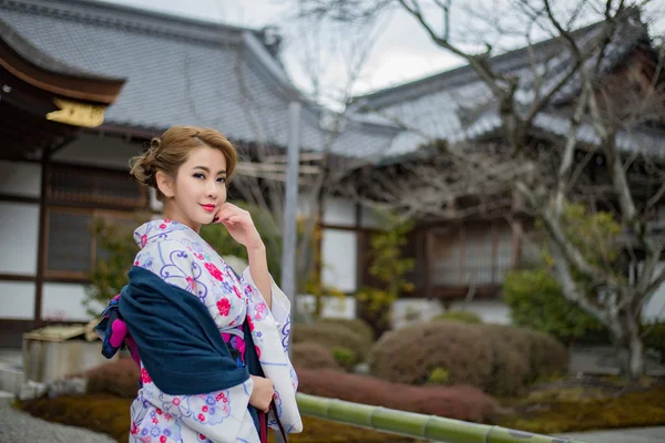 Kvinna klädd i traditionell japansk dräkt promenader under tori — Stockfoto