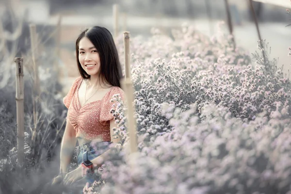 Mooie jonge vrouw reiziger op zoek bloemen veld zitten op — Stockfoto