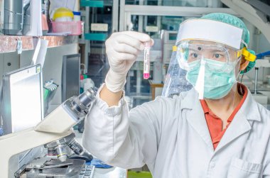 Coronavirus covid 19 salgın hastalığı. Doktor ya da laboratuvar teknisyeni Tayland hastanesindeki laboratuvarda kan örneği tüpü tutuyor.