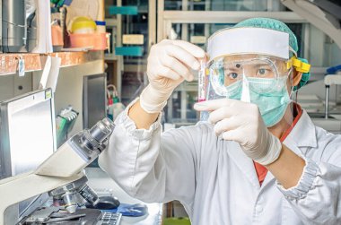 Coronavirus covid 19 salgın hastalığı. Doktor ya da laboratuvar teknisyeni Tayland hastanesindeki laboratuvarda kan örneği tüpü tutuyor.