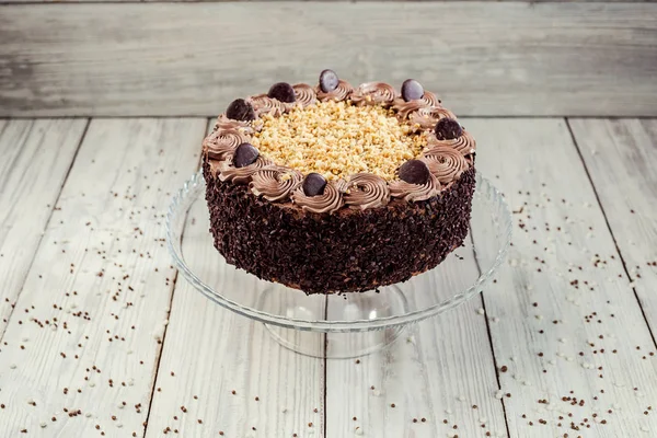 Pastel vegano de chocolate negro con caramelos y nueces en respaldo de madera — Foto de Stock