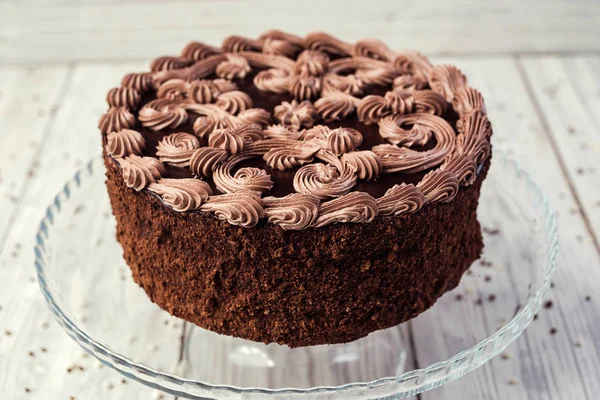 Pastel vegano de chocolate negro con caramelos y crema en respaldo de madera — Foto de Stock