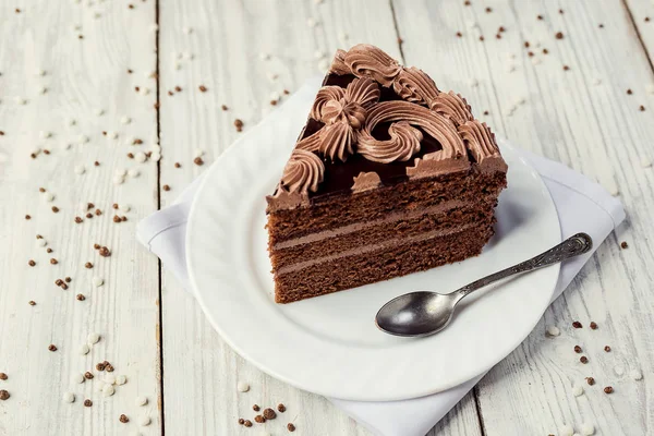 Pastel vegano de chocolate negro con caramelos y crema sobre fondo de madera — Foto de Stock