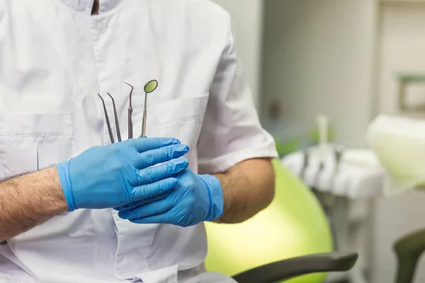 Dentista masculino com ferramentas sobre o fundo do consultório médico. Saúde, profissão, estomatologia e medicina conceito — Fotografia de Stock