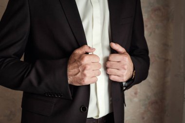 İş adamı ceket giyiyor, erkek eli kapalı, damat düğün töreninden önce hazırlanıyor.