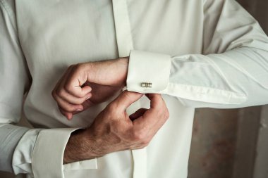 İş adamı beyaz gömlek giyer, erkek eli yakın durur, damat düğün töreninden önce sabah hazırlanır.