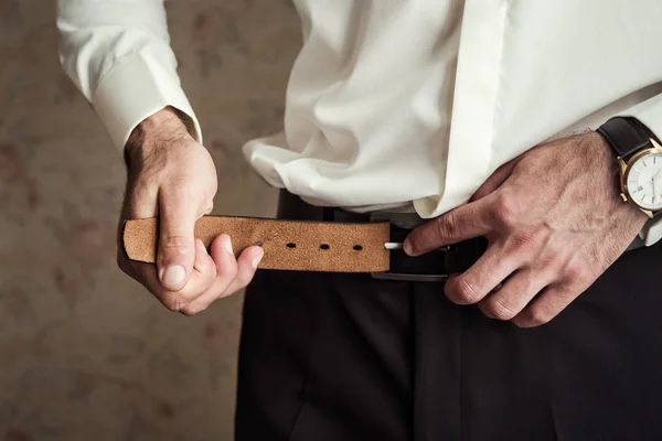 Affärsman sätta på ett bälte, mode och kläder koncept, brudgummen gör sig redo på morgonen före ceremonin — Stockfoto